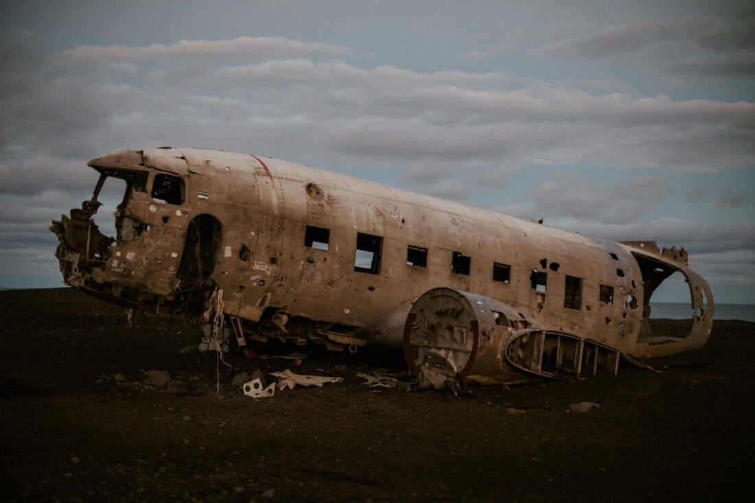 Lindsay standing beside the abandoned plane wreck under Iceland's midnight sky