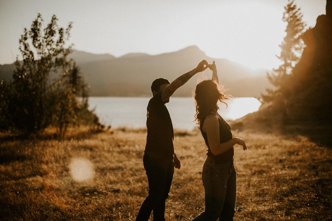 Wide shot of the couple silhouetted against the Mt. Hood skyline, later in the golden hour session