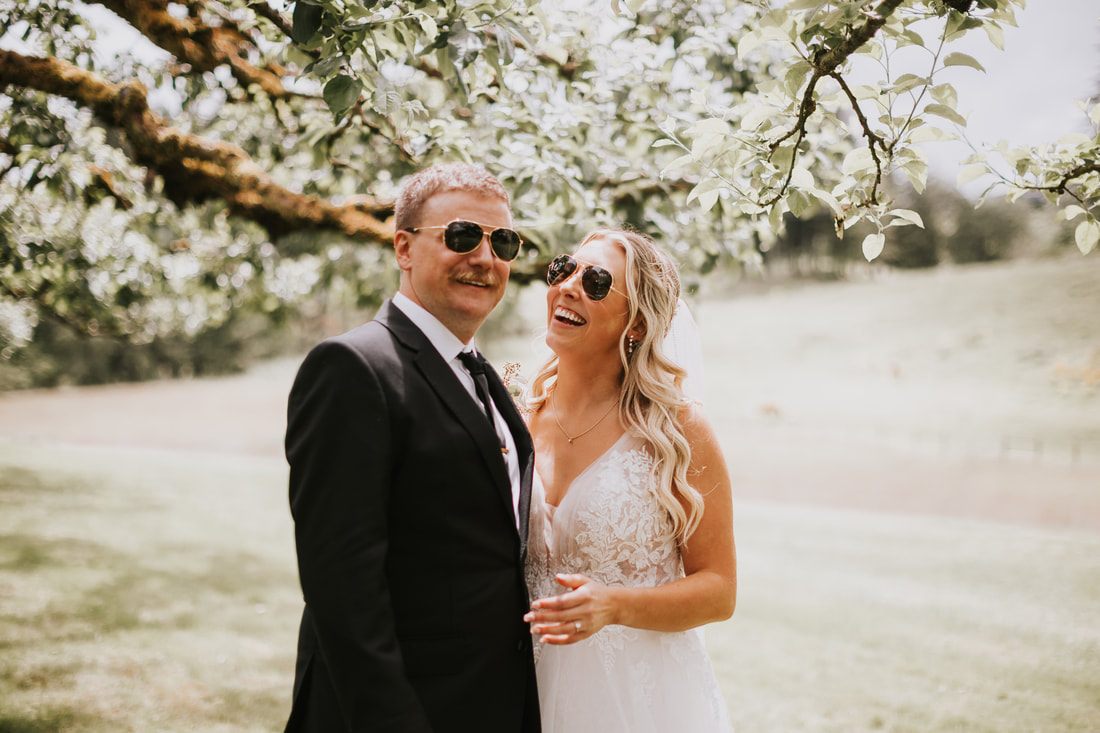 Bride and groom exchanging vows under a handmade wooden altar at the orchard.