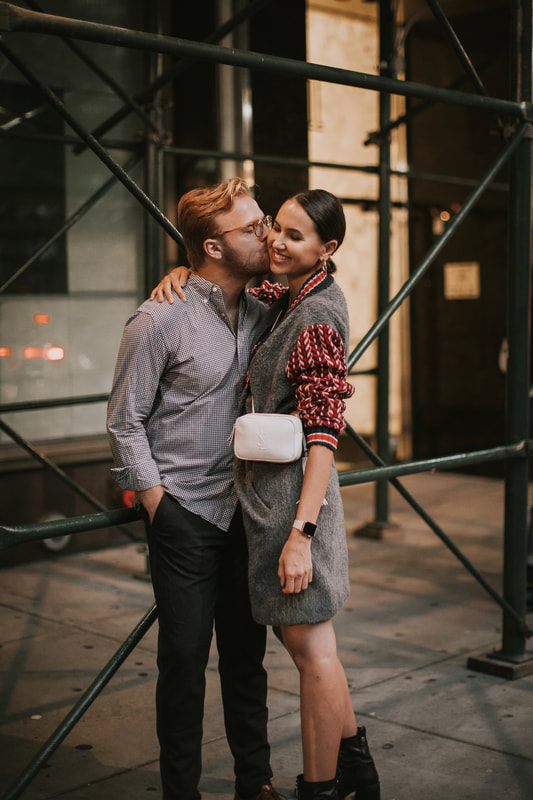 Engagement portrait as Karina and Matt embrace under evening city lights