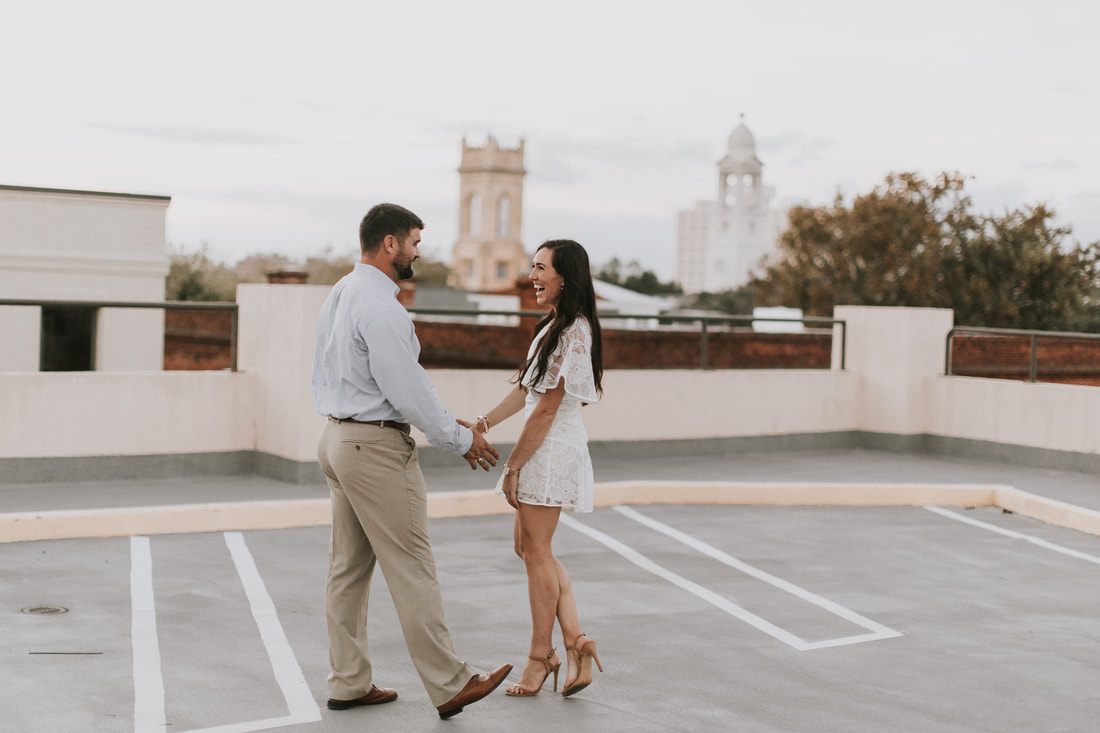 The engaged couple walking down a brick alley in a downtown Charleston alley with exposed brick