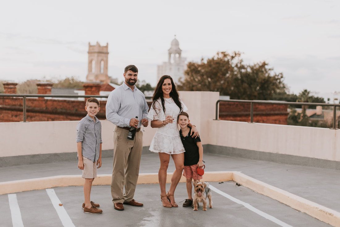 The family posing on a rooftop in a downtown Charleston alley with exposed brick