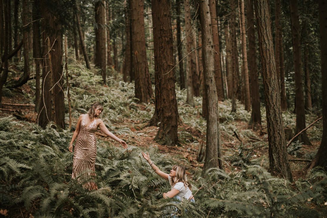 Two women in evening gowns embracing the wild forest setting during their brand shoot