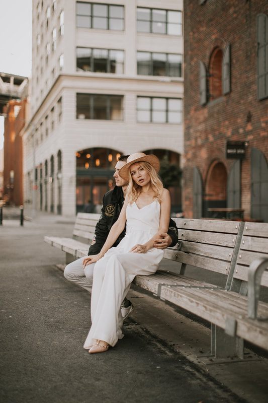Engaged couple walking hand in hand across the Brooklyn Bridge at sunrise