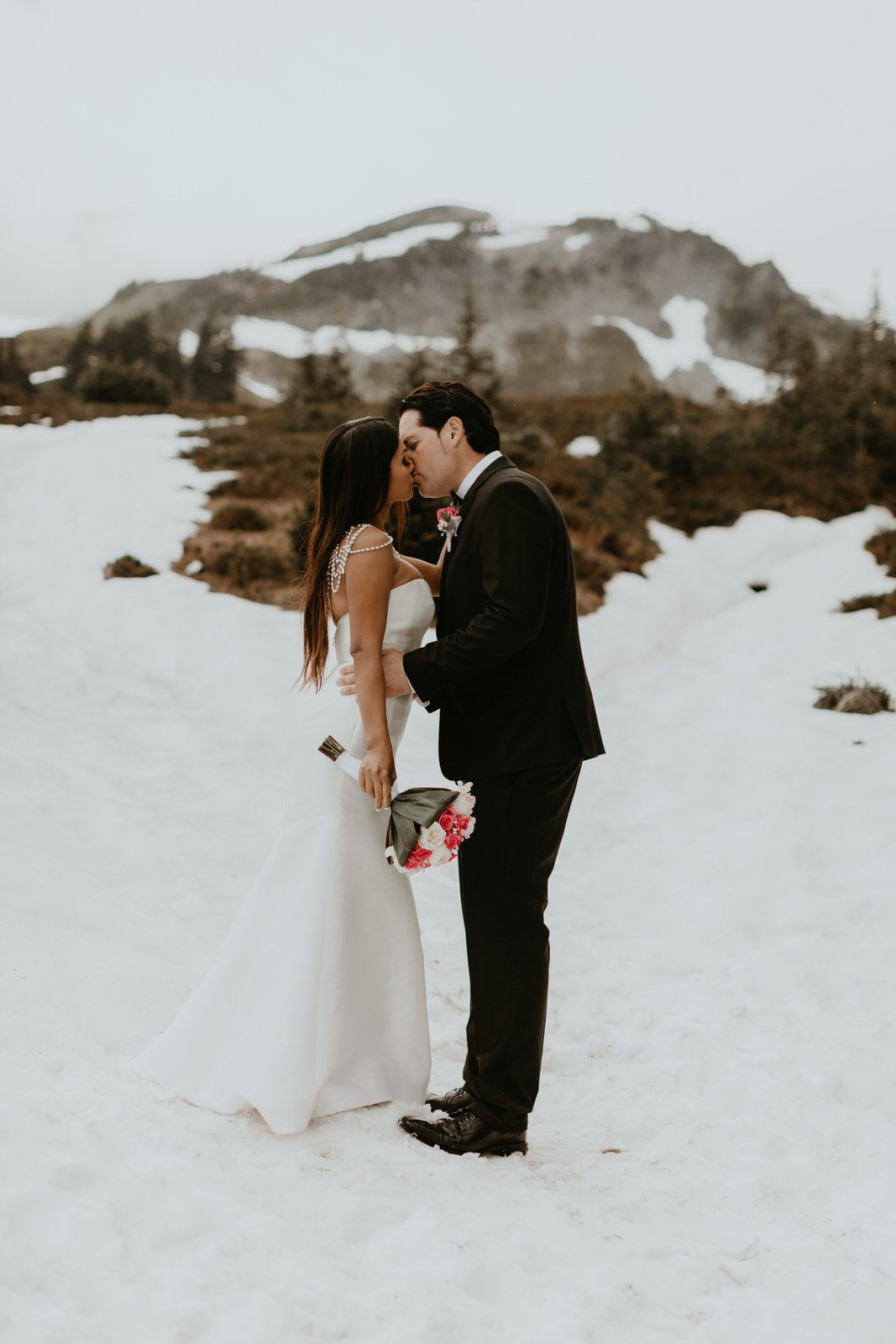 Bride's ivory gown catching the light against dark trees at Mt. Rainier.