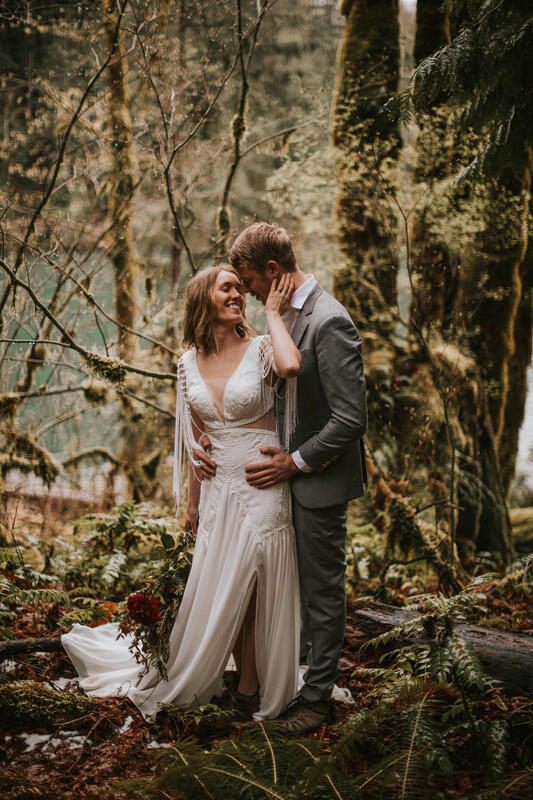 Bride and groom walking together through tall evergreens