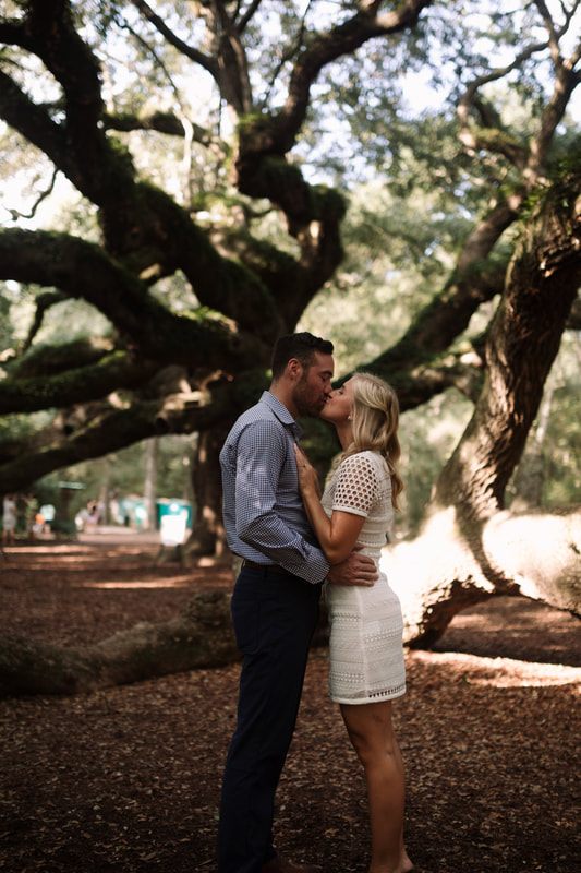 The couple posing beside ancient oak limbs near the historic oak trees canopy