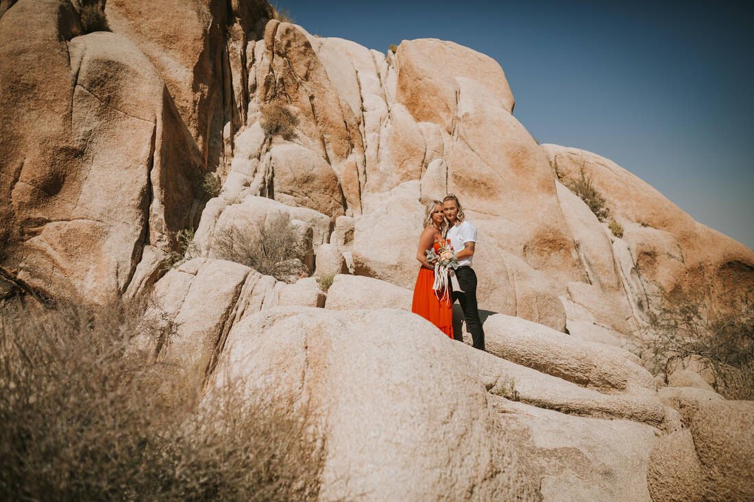 Ciarra and AJ stand together with Joshua trees framing the shot.