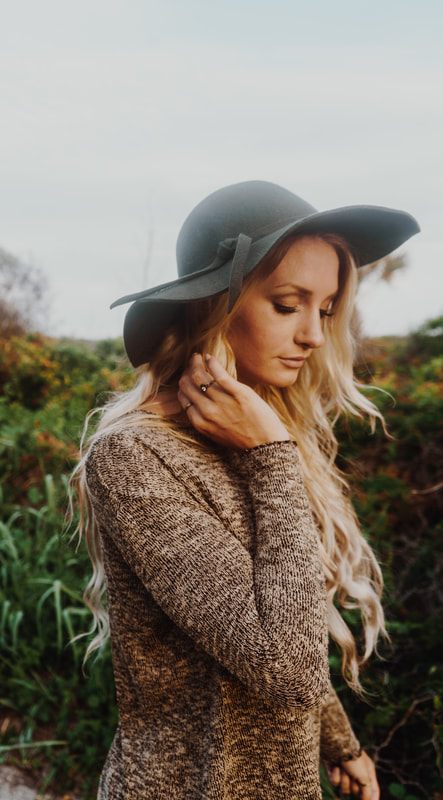 Model wearing a hat and sweater layered look at Folly Beach.