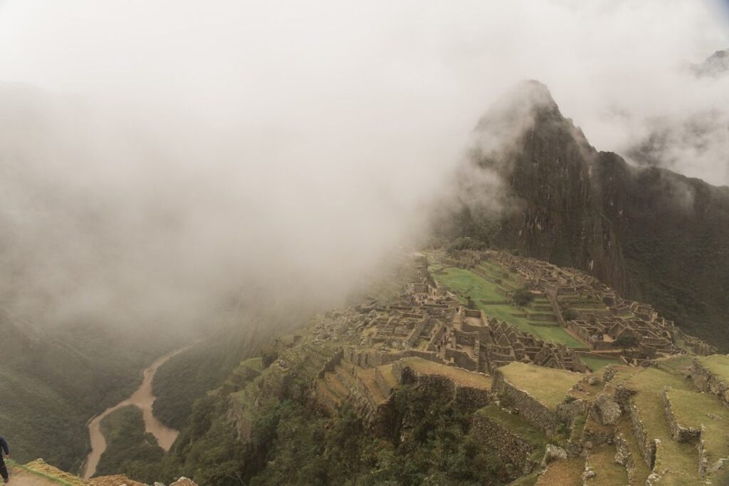 Wide shot of Machu Picchu with clouds settling into the valley