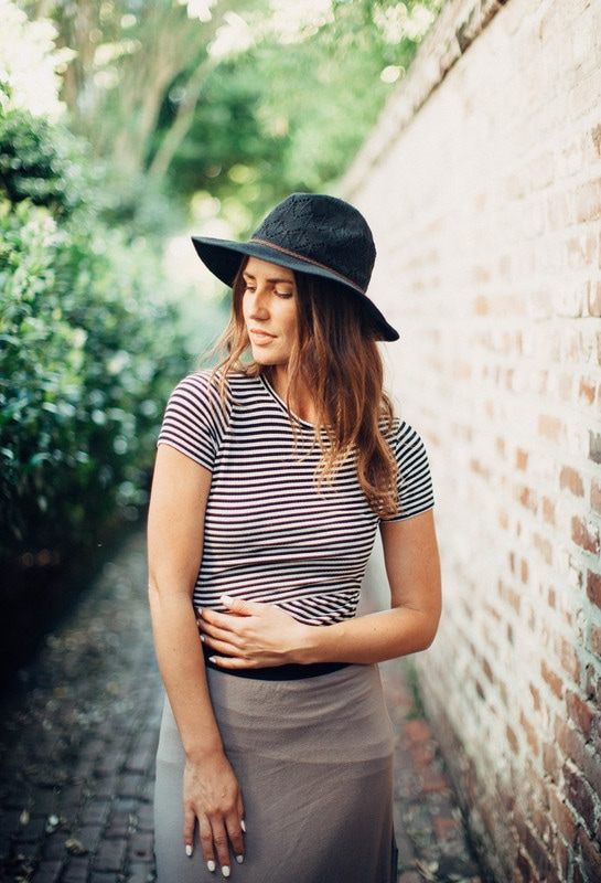 Susan posing against a brick wall in a downtown Charleston alley