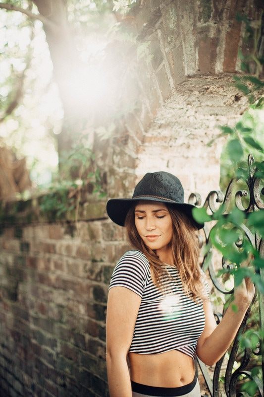 Susan posing against a brick wall in a downtown Charleston alley
