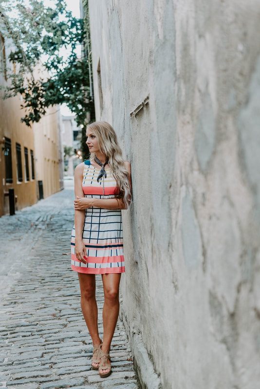 Lindsey O smiling candidly on a Charleston cobblestone street during a portrait session