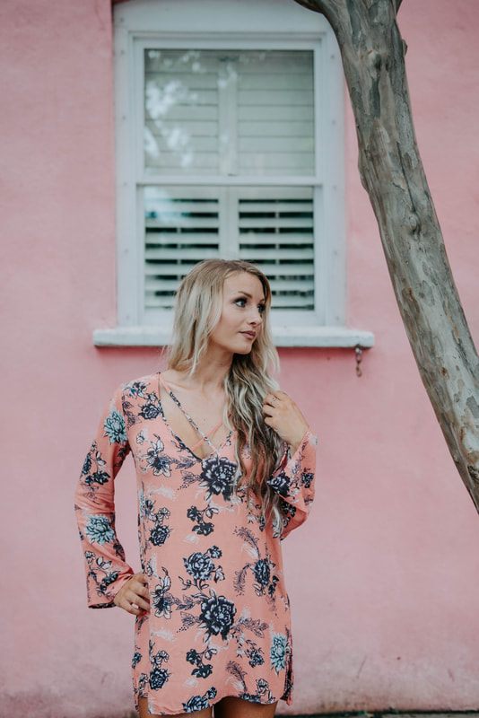 Lindsey O posed near a flowering vine wall in downtown Charleston