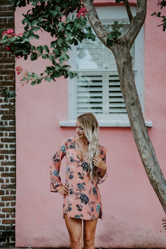 Lindsey O strolling through a shaded Charleston alleyway during golden hour