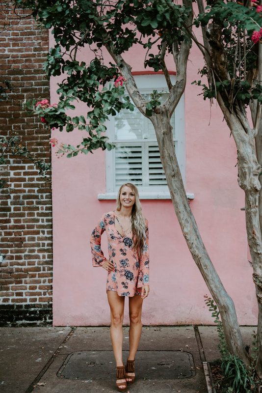 Lindsey O walking through a Charleston courtyard framed by iron gates