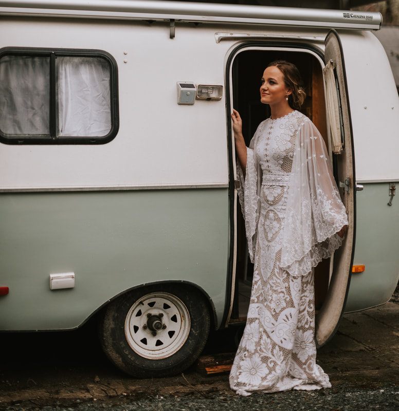Detail shot of Tanya's antique-style ivory wedding gown against dark trees.