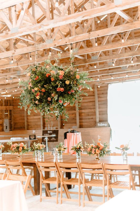 The bride and groom embracing warmly under string lights at the barn