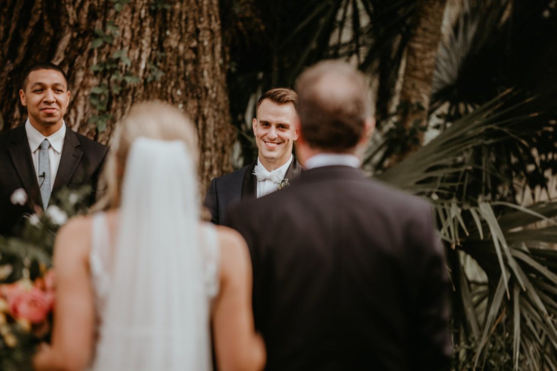 Alexis and Max laughing together under string lights at the barn