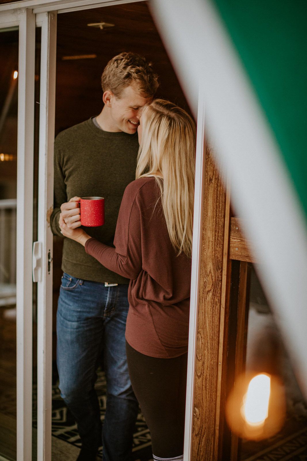 Couple embracing near the entrance of their a-frame cabin
