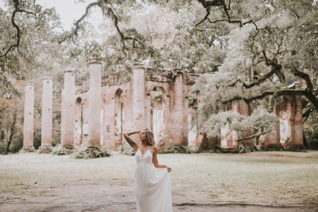 Bride in a simple white dress with layered sleeves posing for bohemian bridal portraits in Charleston.