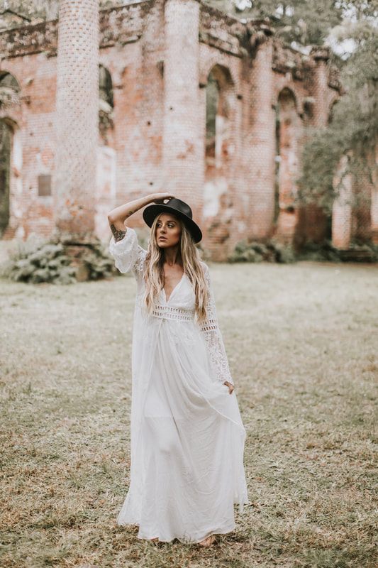Charleston bride in a bohemian floral crown standing amid historic ruins architecture.