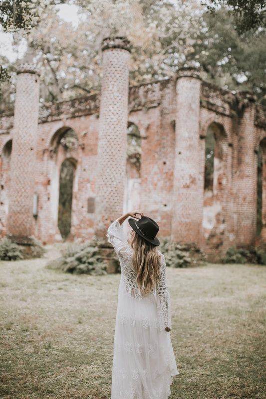Bride in a simple white dress with layered sleeves posing for bohemian bridal portraits in Charleston.