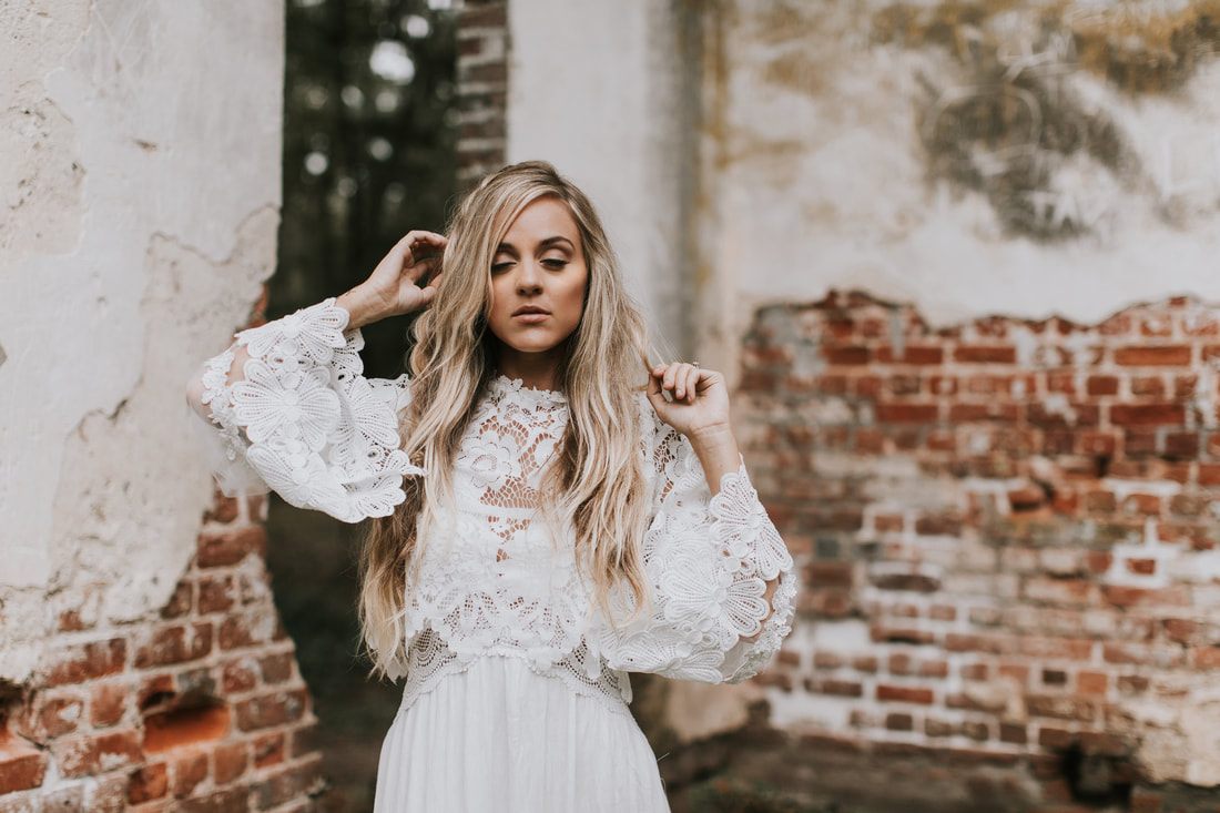 Bride in a simple white dress with layered sleeves posing for bohemian bridal portraits in Charleston.