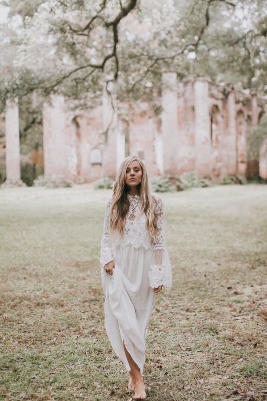 Bride in a simple white dress with layered sleeves posing for bohemian bridal portraits in Charleston.