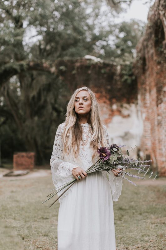 Charleston bride in a bohemian floral crown standing amid historic ruins architecture.
