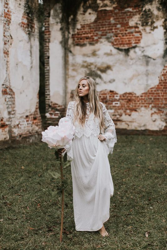 Bride in a simple white dress with layered sleeves posing for bohemian bridal portraits in Charleston.
