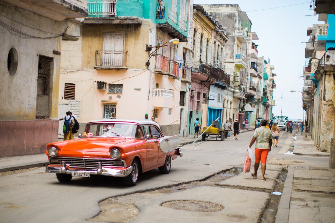 Brightly painted vintage American car parked on a colorful street in Havana, Cuba