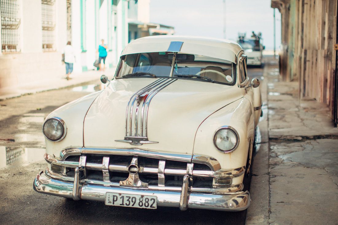 Vintage car parked beside a weathered colonial building in Havana