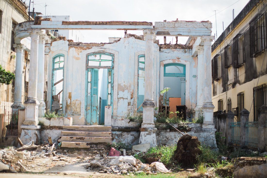 Vintage car parked beside a weathered colonial building in Havana