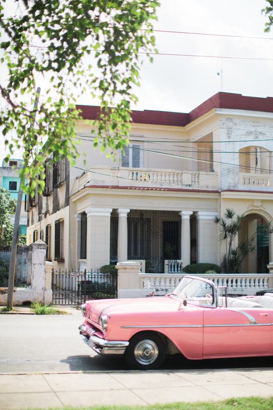 Brightly painted vintage American car parked on a colorful street in Havana, Cuba