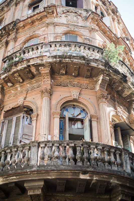 Vintage car parked beside a weathered colonial building in Havana
