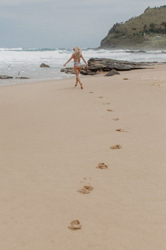 Walking along rocky coastline in a Cheeky Swim bikini near Sydney