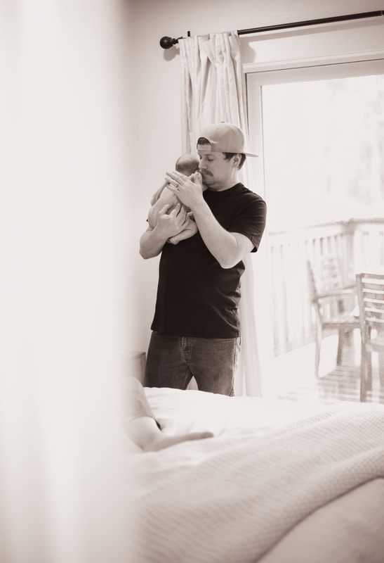 Father holding his newborn daughter near the nursery window