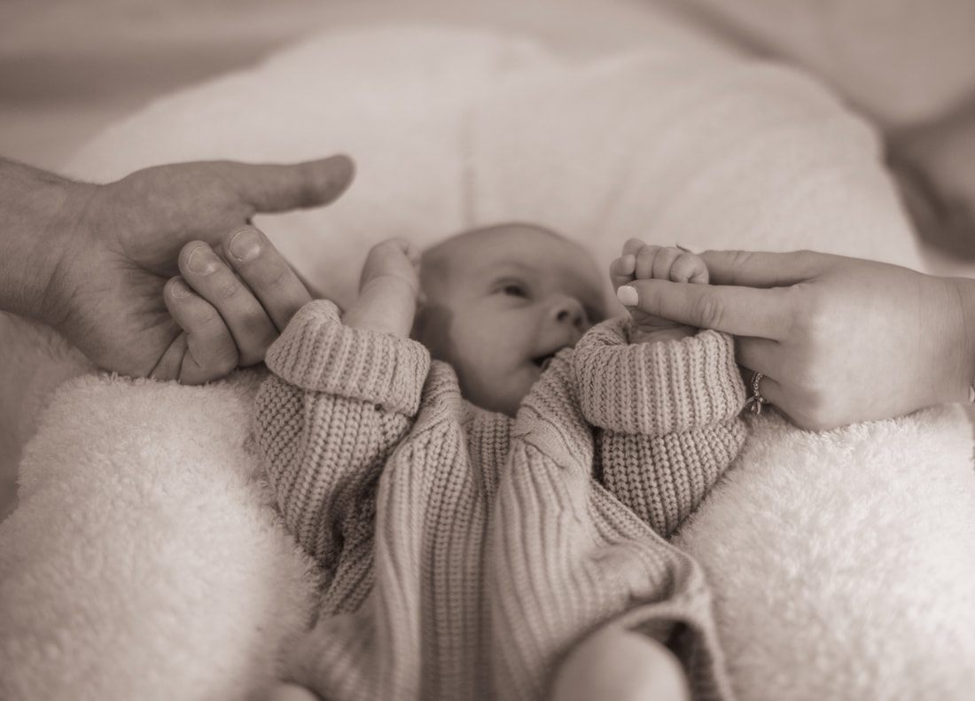 Mother gently cradling her newborn daughter by the window