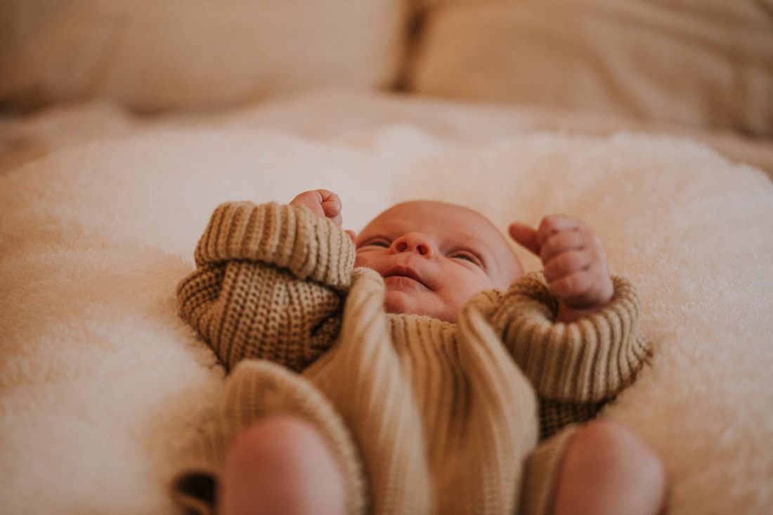 Close-up of a newborn baby's tiny hand resting on a swaddle