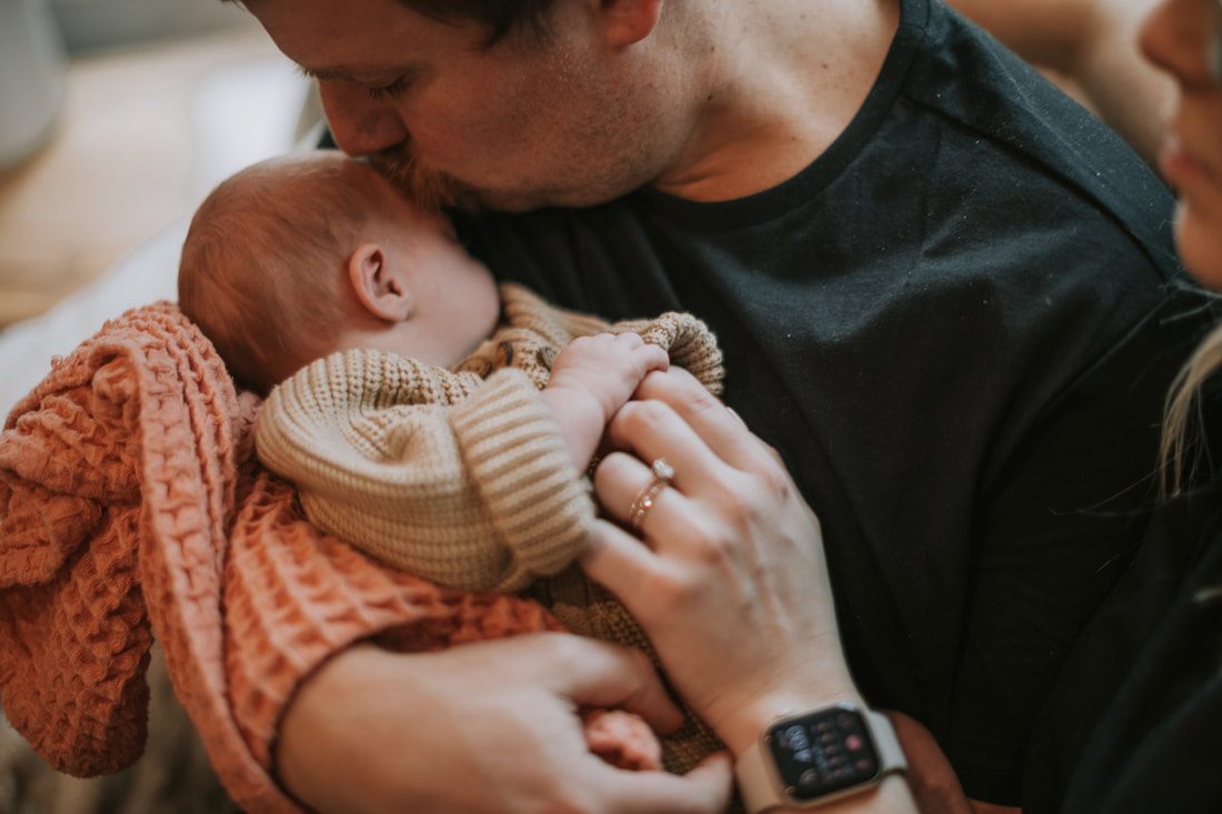 Family portrait of new parents cradling their newborn daughter