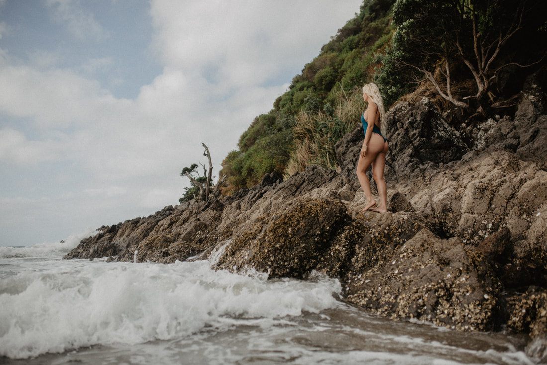 Model walking along the shoreline in a Strange Bikinis swimsuit, New Zealand.