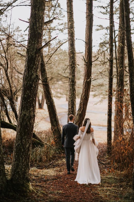 Newlyweds walking hand in hand through the woods