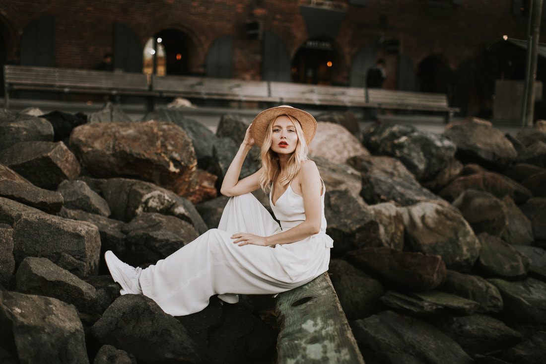 Valentina leaning against a Brooklyn storefront in her bridal romper