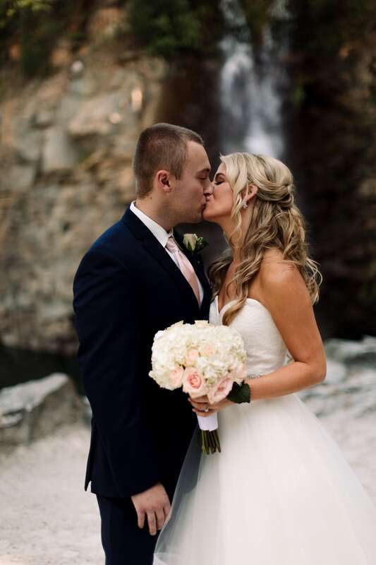 Wide shot of the wedding couple with the waterfall cascading behind them