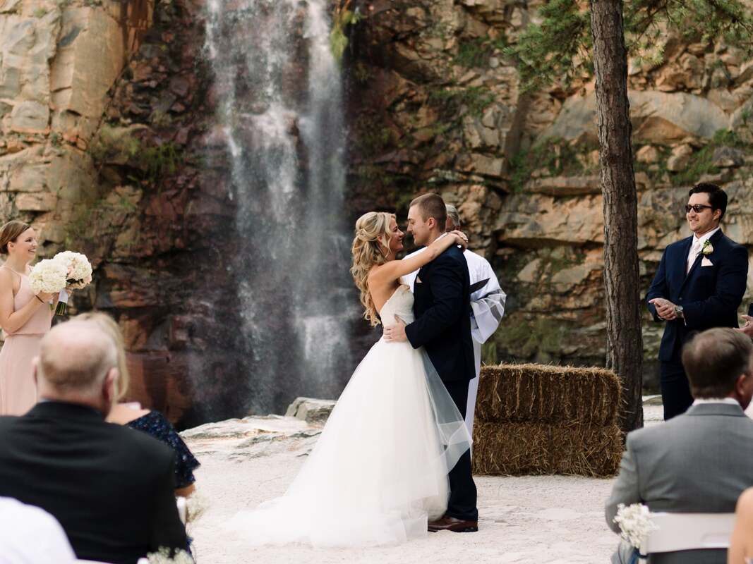 Groom helping the bride across the rocky waterfall terrain