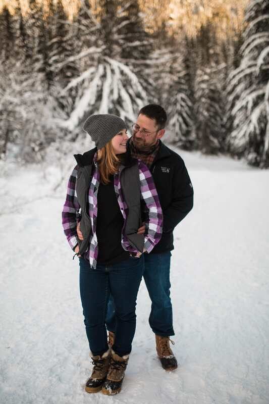 Kristi and Brian embracing beside a frozen alpine lake in the Snoqualmie mountains