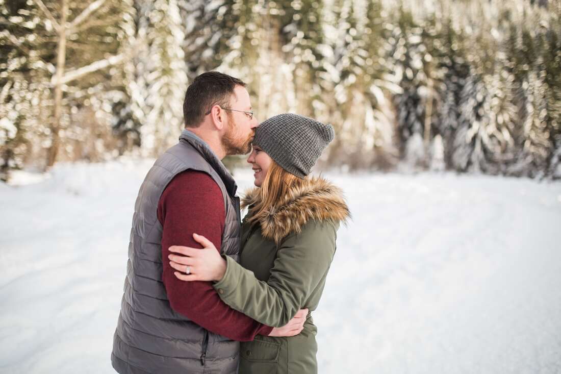 Wide landscape shot of the snow-covered Snoqualmie mountains with the couple in frame