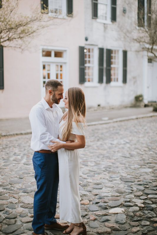 Close embrace between an engaged couple in front of a Charleston historic home