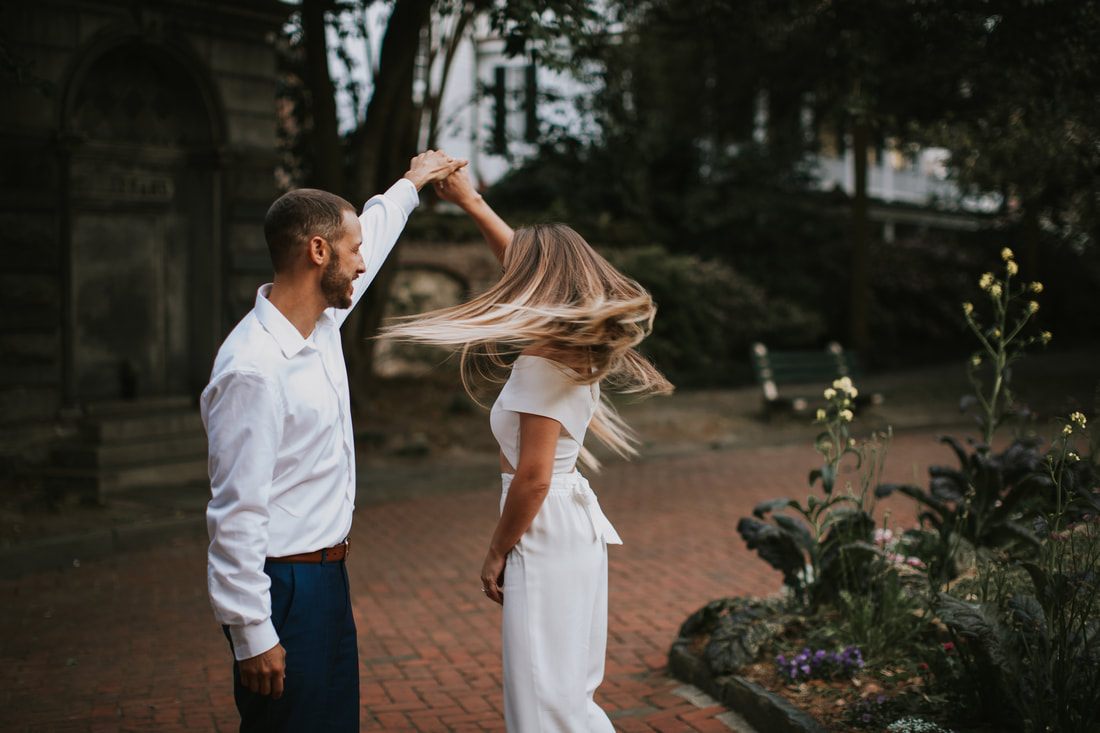 Engaged couple laughing together against a Charleston cobblestone backdrop